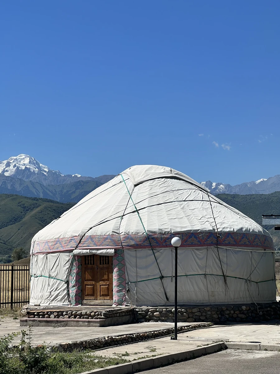 Traditional Kazakh yurt with decorative trim set against snow-capped mountains near Turgen Gorge